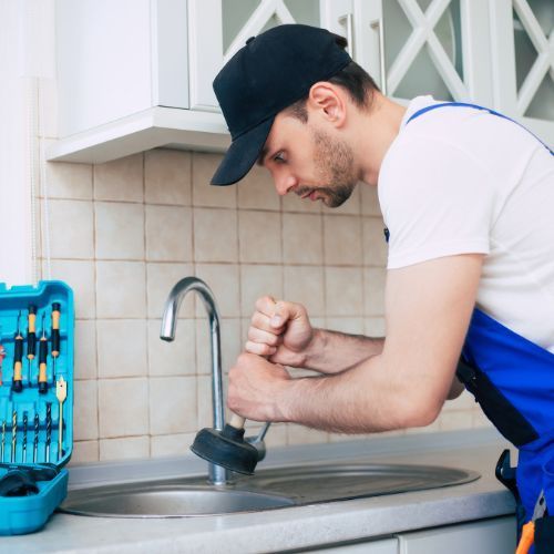 Plumber working on kitchen sink repair in Gaston County
